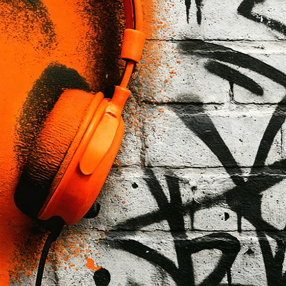 Orange Headphones Rough - Arts To GloryOrange Headphones RoughDigital Wall ArtArts To GloryClose - up of vibrant orange headphones set against graffiti, representing urban style and resilience by Arts To Glory.