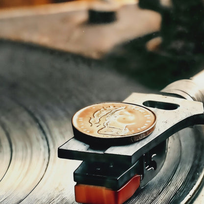 Video showcasing a close-up view of a turntable with a coin-weighted stylus playing an orange label vinyl, perfect for a modern music studio décor.